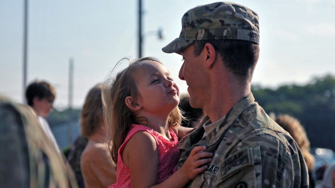 Father in uniform holding young daughter